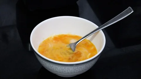 Beating egg bowl fork yellow liquid onion Stock Footage 124939576