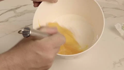 Beating eggs in a bowl in the kitchen with a whisk attachment. 스톡 동영상 239647132