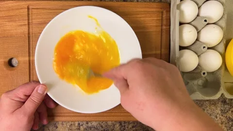 Beating raw chicken eggs in a plate with a fork. Top view. 스톡 동영상 300454055