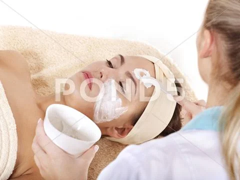 Beautician applying facial mask by woman. Stock Photos
