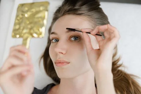 Beautician combing eyebrows of client after lamination treatment Stock Photos