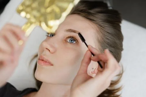 Beautician combing eyebrows of client after lamination treatment Stock Photos