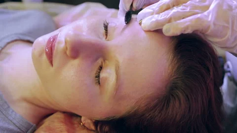 The beautician combs the eyebrows of the client with a special brush 库存影片 119924474