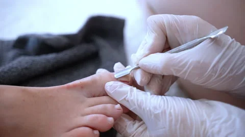 Beautician in disposable gloves using hardware pedicure instrument to remove dry Video stock 230671667