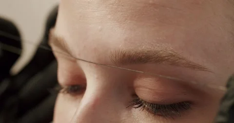 Beautician in gloves using thread to measurements correct shape of eyebrows Stock Footage 256012489