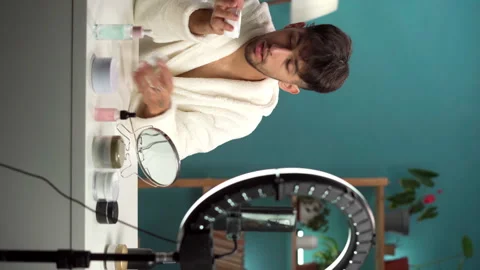 Beautician making makeup tutorial on smartphone at home. Arabic male blogger in Vídeos de archivo 257315959