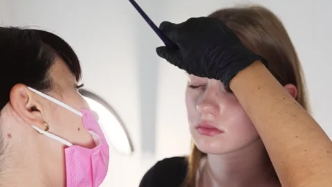 Beautician marking brows using brush and ruler before tattoo Stock Footage 316429885