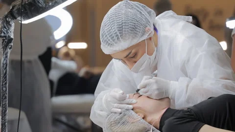 Beautician performing microblading procedure on client's eyebrows, sterile Stock Footage 308488982