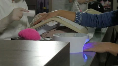 Beautician treatment in nail salon, hands closeup, drying nails on device. Video stock 59743891