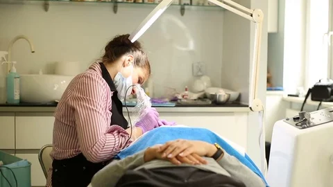 Beautician using apparatus while doing permanent makeup to a client  Stock Footage 76029870