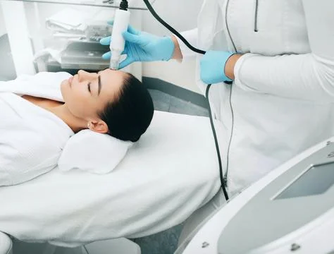 Beautician using machine no-needles mesotherapy smoothes wrinkles of the skin Stock Photos