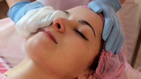 Beautician wipes the woman's face with a white towel Video stock 73855853