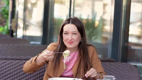 A beautiful 30-year-old young woman in a restaurant on the street picks up .. Stock Footage 242255480