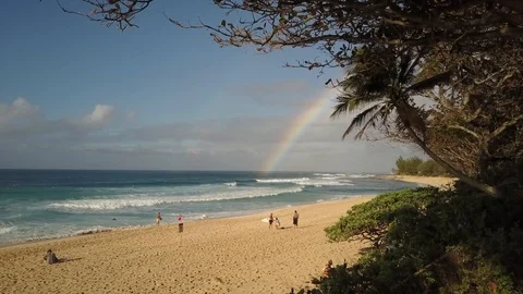 Beautiful 4k drone shot of Oahu Hawaii Sunset Beach. Rainbow, waves and surfers Stock Footage