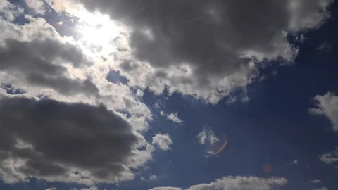 Beautiful 4K time lapse. Sun rays break through white fluffy clouds on vivid Stock Footage 129633900