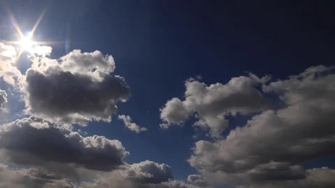 Beautiful 4K time lapse. Sun rays break through white fluffy clouds on vivid Stock Footage 129637476