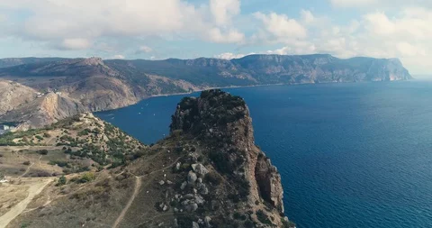 Beautiful aerial 4k video of the rock with blue sea, sand, sky, sun and clouds. Stock Footage 128697853