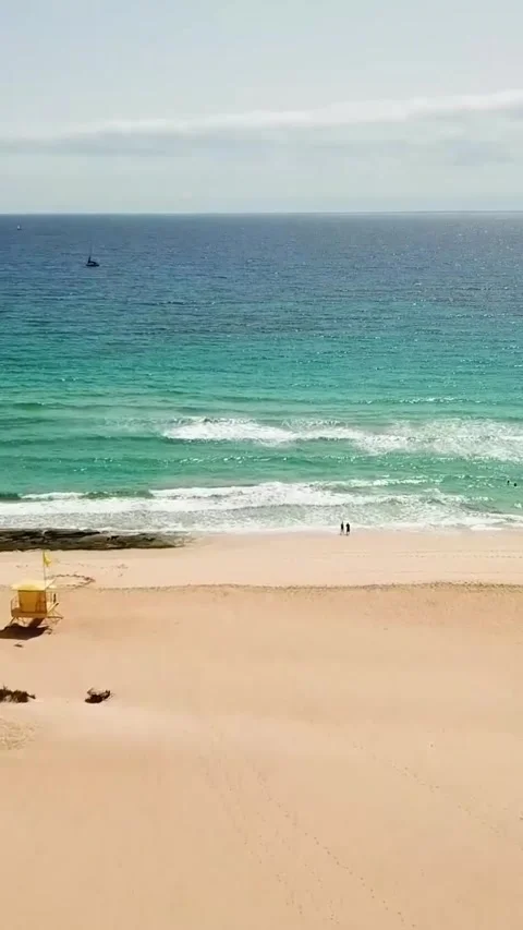 Beautiful aerial view flying forward over a vast sandy beach with a lifeguard Stock Footage 344841217