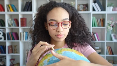 Beautiful african american female student spinning and watching the globe in her Stock Footage 104450153