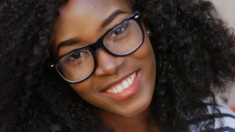 Beautiful African curly-haired young woman with brown eyes in glasses smiling Stock Footage 81834945