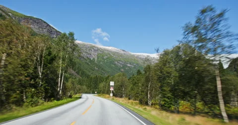 Beautiful alpine landscape featuring winding highway and snowy mountain backdrop Stock Footage 321319694