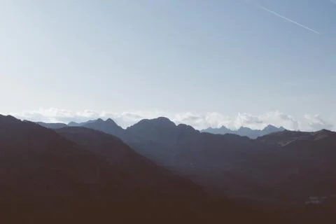 Beautiful alpine landscape with mountain range silhouette during sunset. Stock Photos