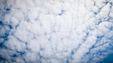 Beautiful altocumulus clouds float across vast blue sky at noon. Stock Photos