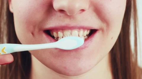 Beautiful and cute woman brushing her teeth. A girl stands on a white Stock Footage 59311252