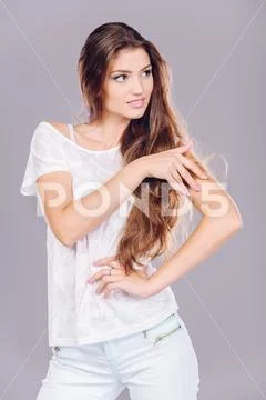 A beautiful and cute young lady is posing over grey background. Fashion conce Stock Photos