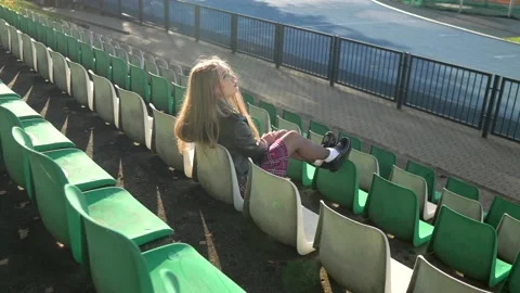 Beautiful and passionate girl in a biker jacket alone sits in an empty stadium. Stock Footage