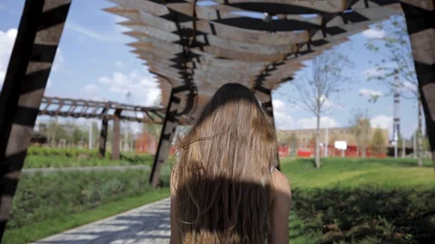 Beautiful and pretty girl of model appearance is walking in shadow of industrial Stock Footage 111165341