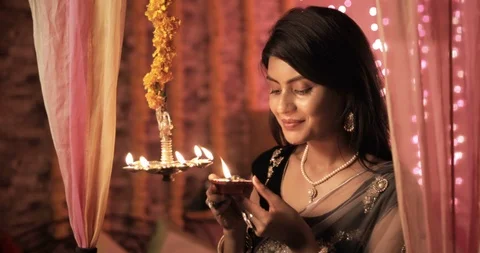 A beautiful and traditional woman lighting a lamp (Diya) during Diwali festival. Vidéo gratuite 93710428
