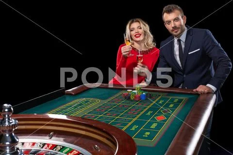 Beautiful and well dressed couple playing roulette in the casino Stock Photos