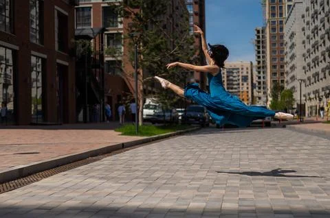 Beautiful Asian ballerina dancing outdoors. Urban landscape. Grand jete. Stock Photos