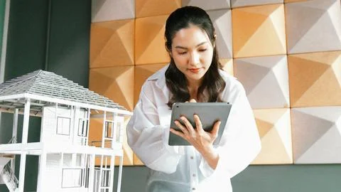 Beautiful asian project manager using tablet check house model. Manipulator. 库存照片