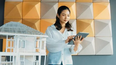 Beautiful asian project manager using tablet check house model. Manipulator. Stock Photos