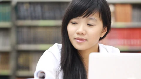 Beautiful asian student using laptop and reading book in library Stock Footage 35501118