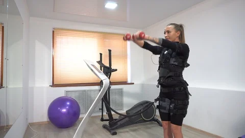 Beautiful athletic brunette doing EMS exercises with dumbbells. Hand exercises Stock Footage 102362366