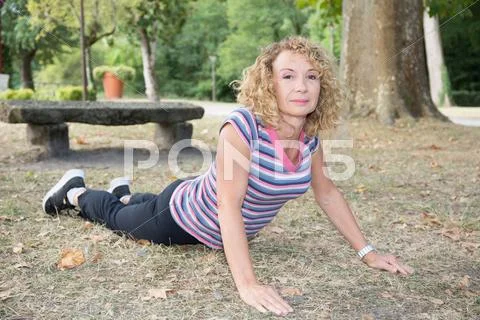 Beautiful athletic mature girl doing yoga outside- crocodile pose Stock Photos