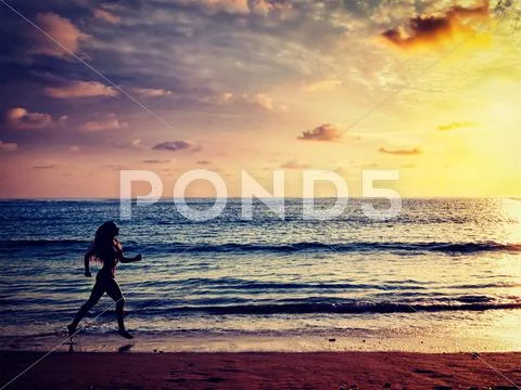 Beautiful athletic woman running along sea on the beach Stock Photos