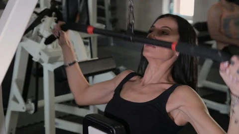 Beautiful athletic young girl performs a pull on the chest simulator in the gym. Stock Footage 103397597