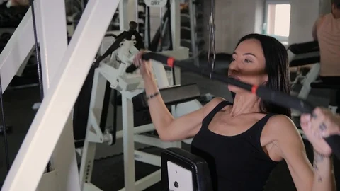 Beautiful athletic young girl performs a pull on the chest simulator in the gym. Stock Footage 103397637