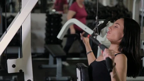 Beautiful athletic young girl performs a pull on the chest simulator in the gym. Stock Footage 103397674