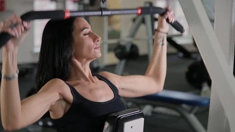 Beautiful athletic young girl performs a pull on the chest simulator in the gym. Stock Footage 103397919