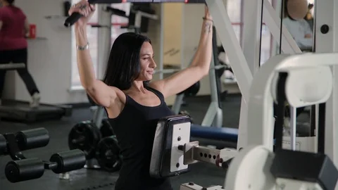 Beautiful athletic young girl performs a pull on the chest simulator in the gym. Stock Footage 103397950