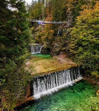Beautiful autumn scenery with cascades on turquoise stream. Suspension footbr Stock Photos