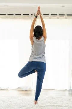 Beautiful back view of a yoga instructor holding the Tree pose with Arms Up.. Stock Photos