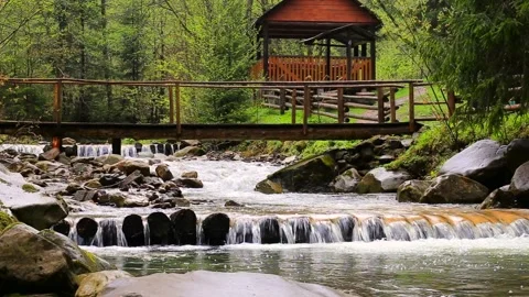 Beautiful background view of cascading river flow under wooden bridge among Stock Footage 143415289