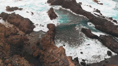 Beautiful bay created from cliffs of frozen lava, a beach with volcanic sand and Stock Footage 112095661