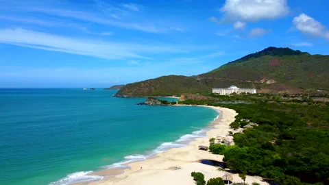 Beautiful beach with a clear blue ocean and a white house in the distance Video stock 292392352